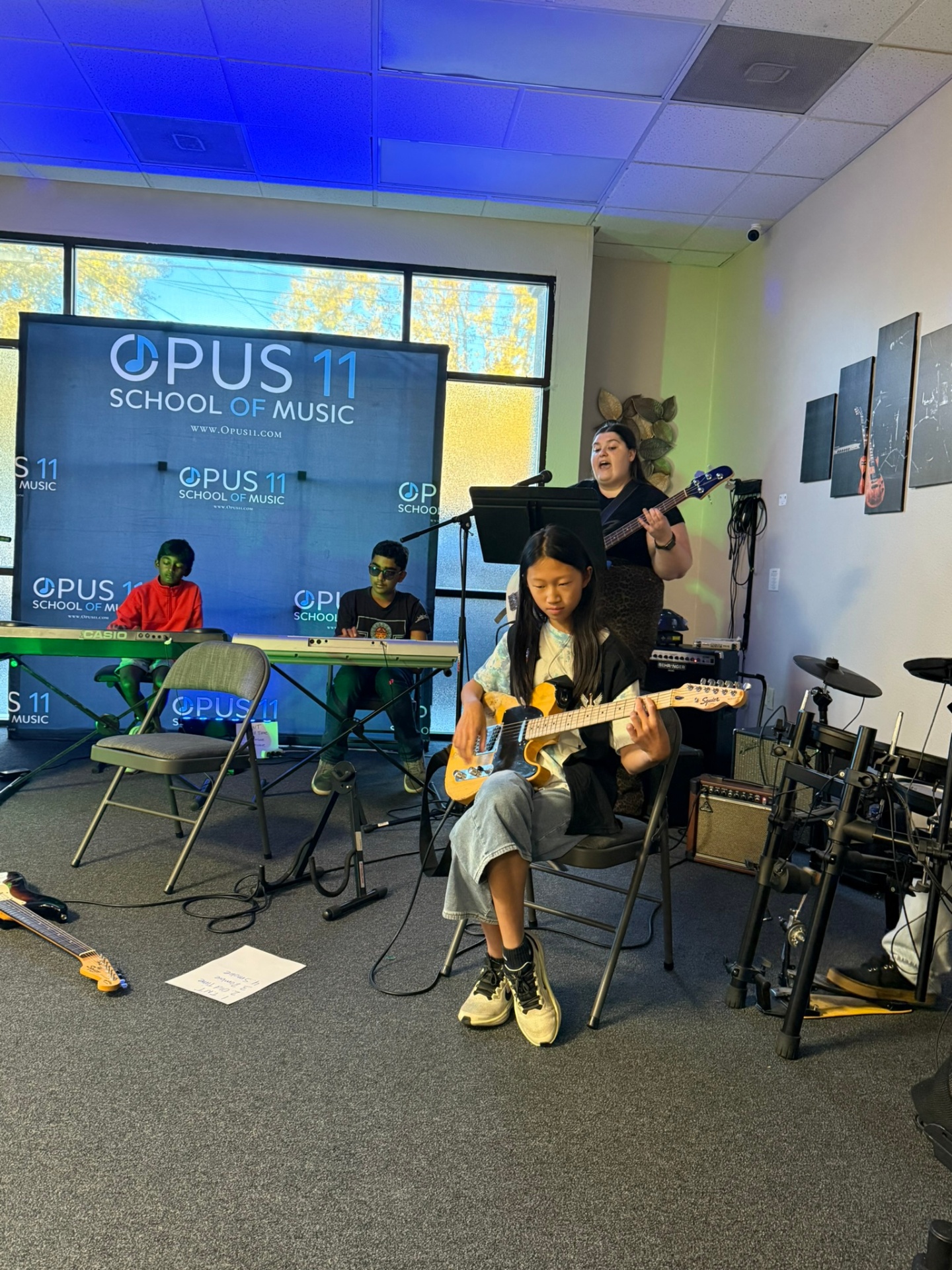 Young musicians playing guitar, keyboard, and drums in an Opus11 group class