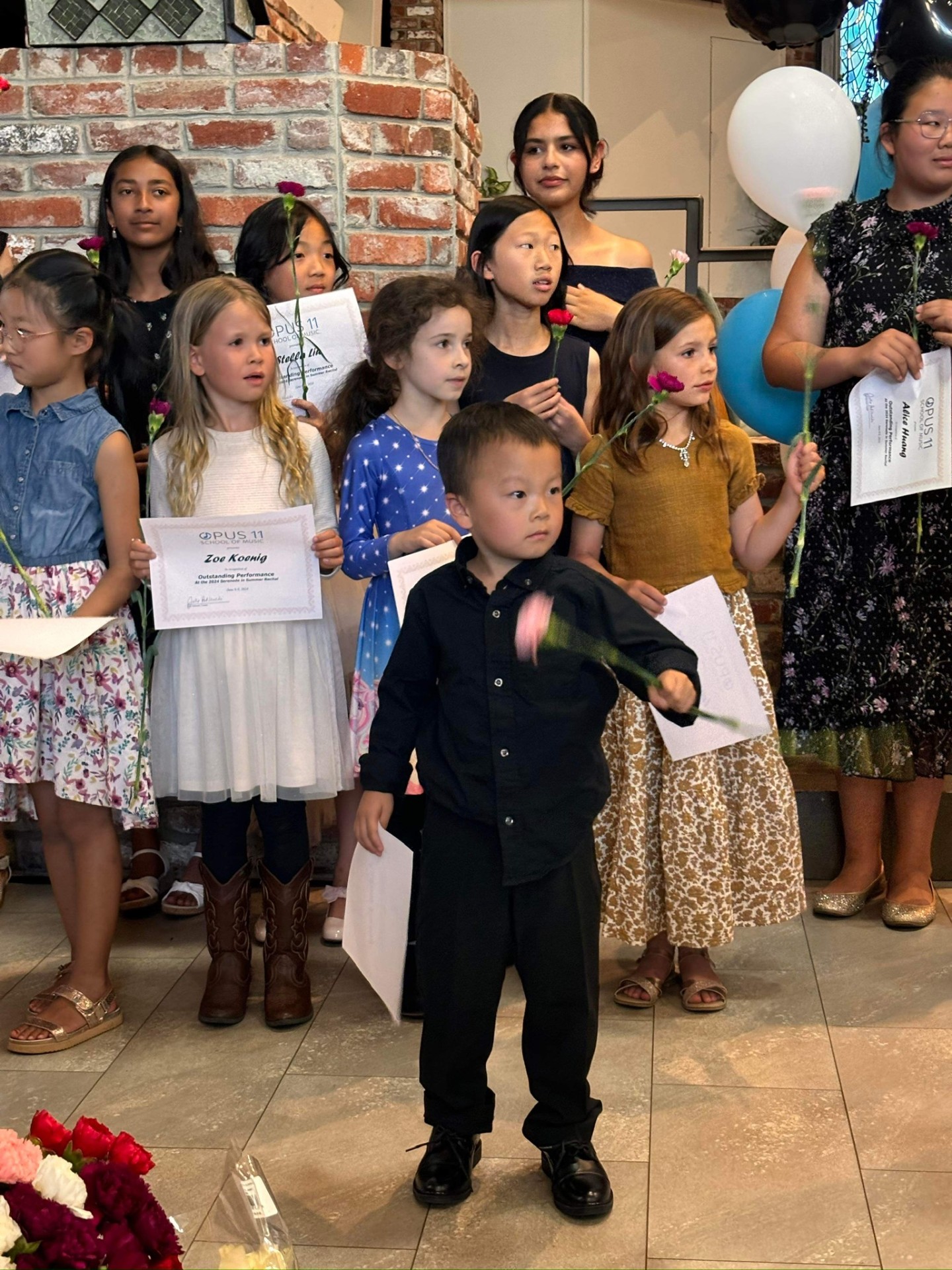 Opus11 students holding certificates and flowers after a recital